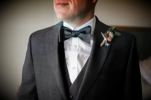 Groom wearing a pine cone and evergreen boutonnière.