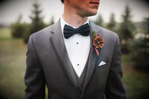 Groom wearing pine cone boutonnière with red plaid ribbon.