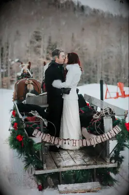 Bride and groom kissing while on a sleigh. 