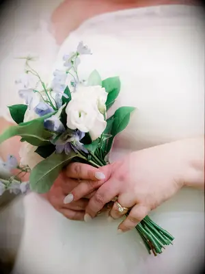 Woman holding a small wedding bouquet blue bell flowers and white roses