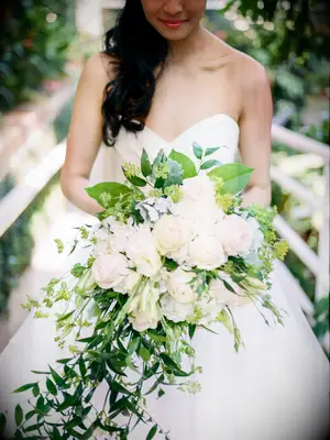 Bride carrying a large bouquet with white roses