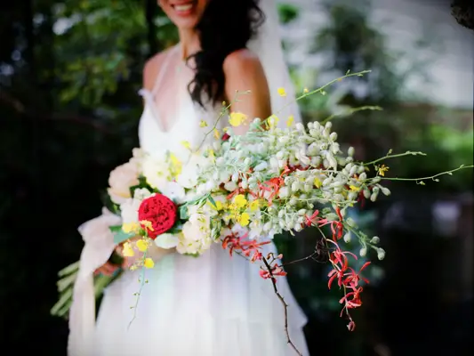 Woman carry large wedding bouquet with white, yellow and red flowers