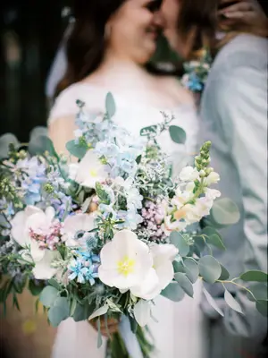 bride holding pastel blue, pink, purple and white wedding bouquet