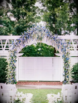 outdoor wedding ceremony venue wih arch of blue flowers at the altar