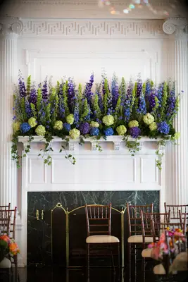 white fireplace mantel decorated with blue, purple and green flowers