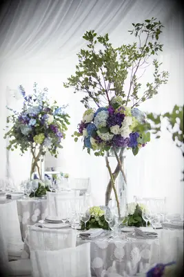 tall wedding centerpieces with tree branches and purple and blue hydrangeas