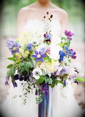 boho purple and blue wedding bouquet with clematis, anemones, thistle, and greenery