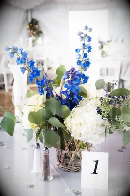 casual wedding centerpiece with blue delphinium, white hydrangeas and eucalyptus in rattan vase