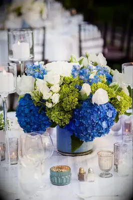 classic wedding centerpiece with blue hydrangeas, green viburnum and white spray roses