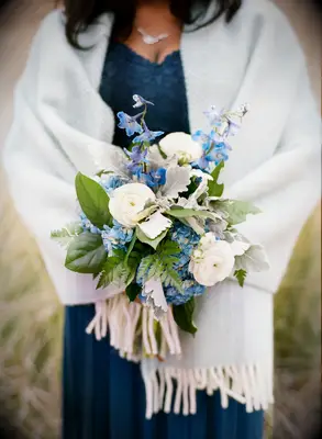 bridesmaid holding small blue and white wedding bouquet with greenery