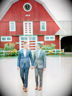Grooms in casual suits in front of Vermont barn
