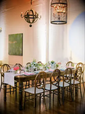 classic indoor wedding reception with long banquet table and wooden infinity chairs