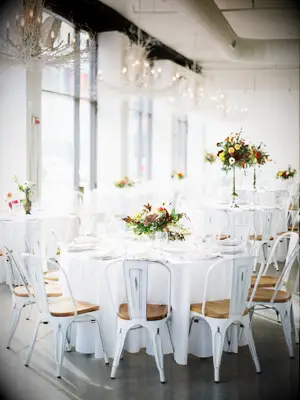 modern wedding reception space with round tables and white marais chairs
