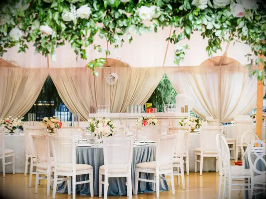 classic wedding reception with round tables and white cane back chairs