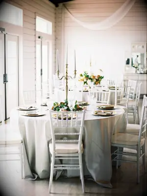 classic wedding reception with round table covered in gray tablecloth and white chiavari chairs