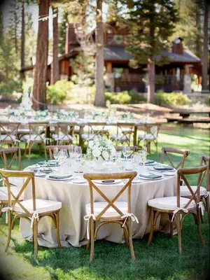 outdoor wedding reception with round tables and wooden cross-back chair