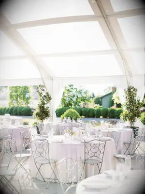 tented wedding reception with round tables and wrought iron english garden chairs in gray color