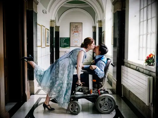 Bride in blue dress kissing groom with foot up