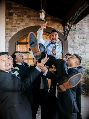 Groomsmen holding up groom for fun wedding photo