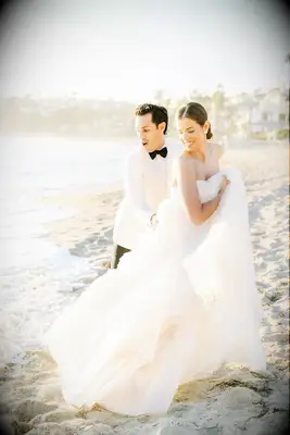 Wave Getting Bride and Groom Wet on Sandy Beach