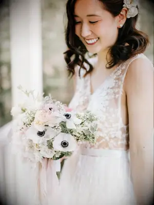 Bride holding anemone bouquet and smiling