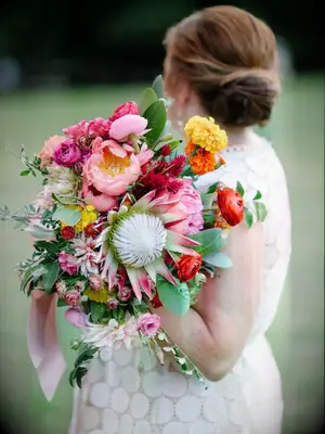 bride holding bright protea bouquet