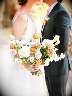 Couple holding white-and-orange wedding bouquet