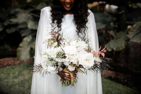 Bride wearing cape and holding bouquet