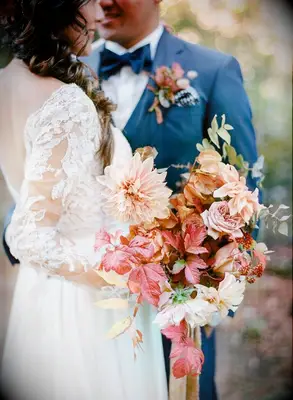 Bride hugging groom while holding fall wedding bouquet
