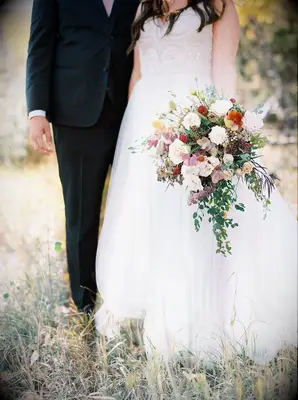 Bride standing by groom and holding bouquet by her side