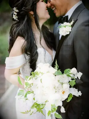 Bride and groom hugging while holding white bouquet