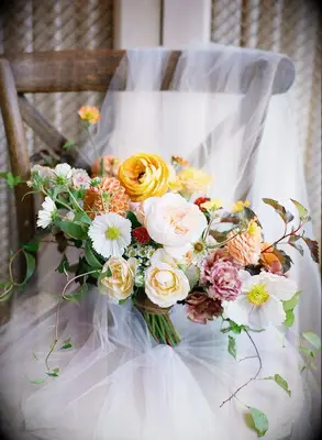 Orange wedding bouquet sitting on chair with veil