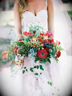 bride holding bouquet with red anemone blooms