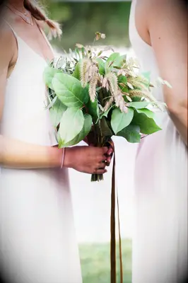 bridesmaid holding simple rustic bouquet with lemon leaves, bay leaves and wheat stalks 