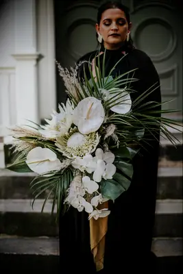 modern oversized greenery wedding bouquet with monstera leaves, palm fronds, white orchids, anthuriums and proteas