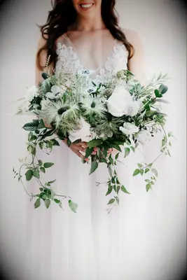 garden style greenery wedding bouquet with white anemones, blue thistle, ruscus and vines hanging down from the bottom
