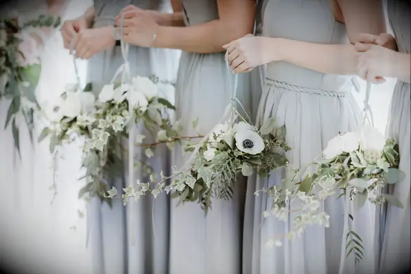 bridesmaids holding unique bouquets of ivy, anemones and greenery tied to ribbon loops