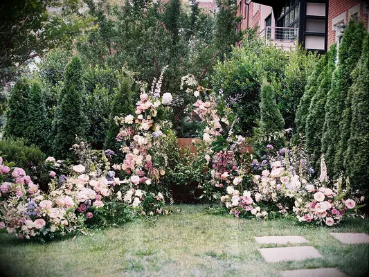 Whimsical pastel floral arrangement around oudoor wedding ceremony altar