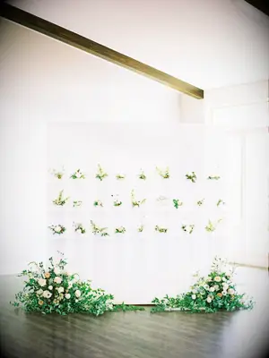 Modern escort card display with small flower pots and large arrangements underneat