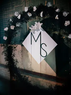 Round floral ceremony arch with white orchids and sleek monogram sign