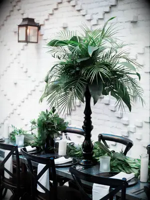 Lush tropical palm leaves as reception centerpieces in sleek black vases