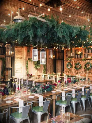 Suspended winter wreath and pine branches at holiday-themed wedding reception
