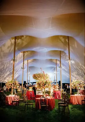 Tented wedding reception with gold uplighting