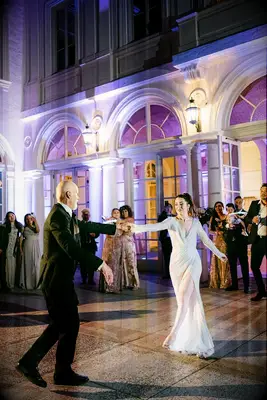 Bride and father sharing dance in courtyard with purple outdoor uplighting