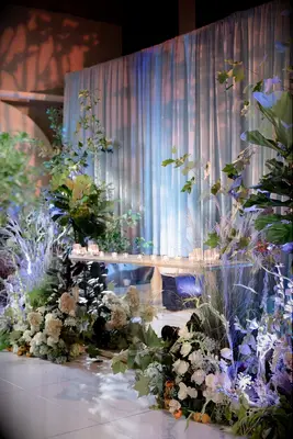 Floral uplighting against white drapery and candlelit table 