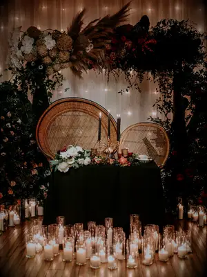 sweetheart wedding table with rattan peacock chairs, black taper candles and white pillar candles on the floor in front