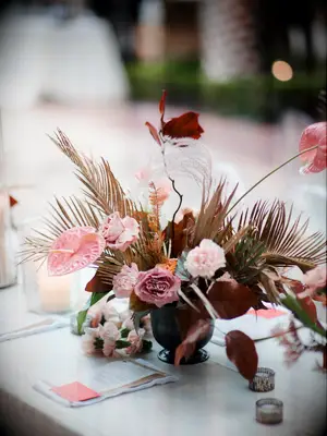 modern fall wedding centerpiece with pink amaryllis, roses, carnations, and burgundy leaves