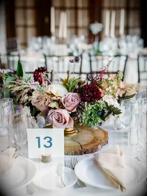 fall wedding centerpiece on wooden base with mauve roses, burgundy dahlias and green hydrangeas