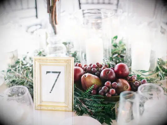 elegant fall wedding centerpiece with red grapes, apples and greenery