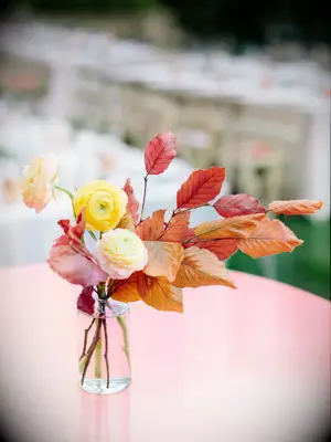 fall wedding centerpiece with orange and red leaves and yellow ranunculus